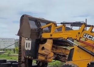 Máquina que caiu de caminhão na BR-420 em Mutuípe é desvirada com auxílio de retroescavadeira