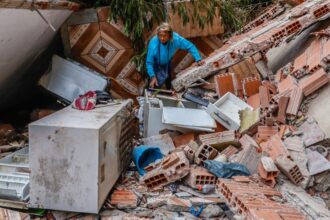 Uma pessoa está no meio de escombros de uma casa destruída pelas chuvas